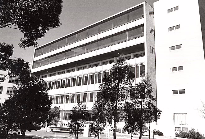 Facade of an old hospital building with trees out the front