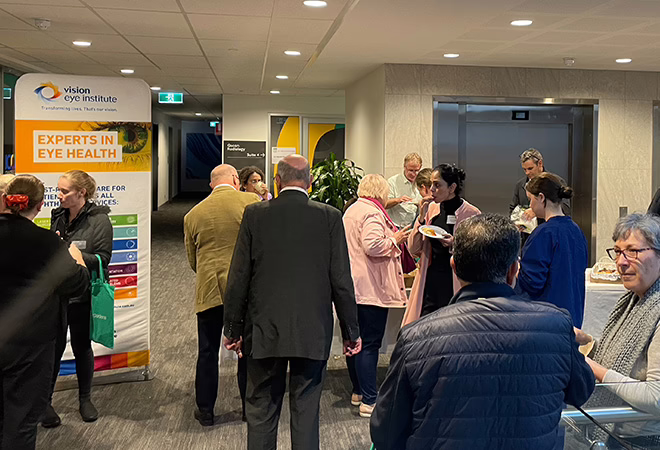 A picture of groups of people in front of a Vision Eye Institute banner at AONA in Melbourne.