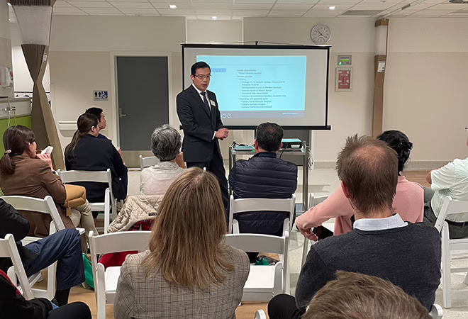 A picture of a clinician presenting at AONA in Melbourne. This picture is taken from the back of the room so that you can see all of the people seated and attending the presentation.