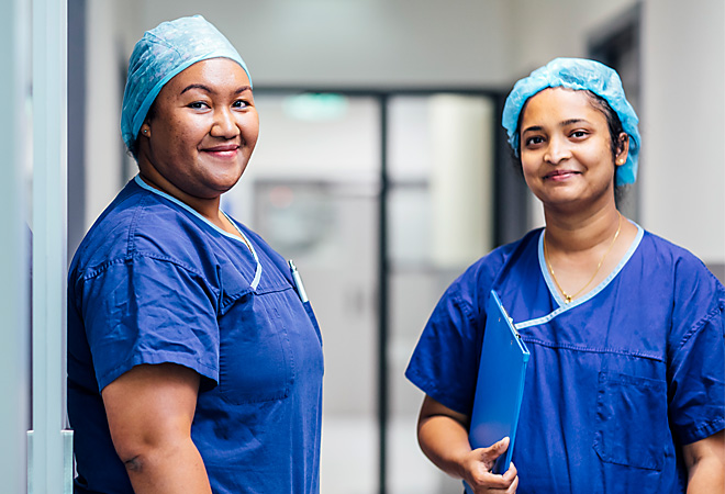 Panch Director of Nursing, Kila Lua, and colleague in scrubs standing in corridor facing camera