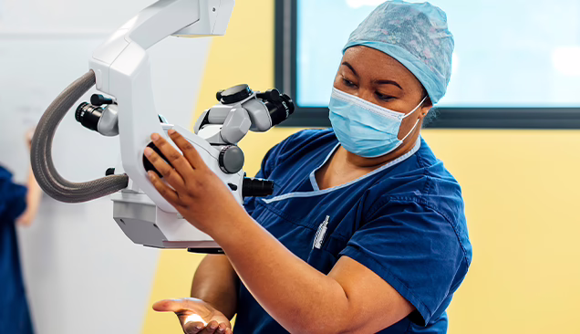 Panch Director of Nursing, Kila Lua in scrubs adjusting position of operating microscope