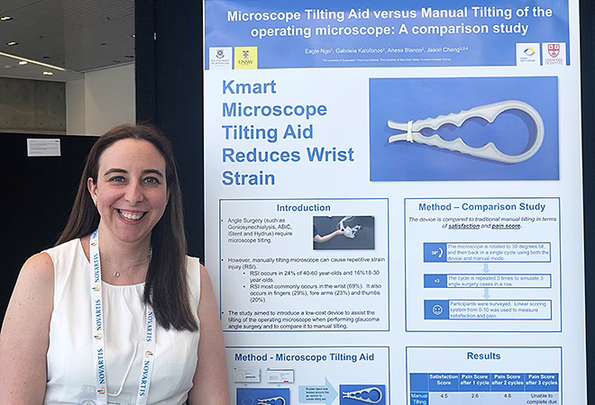 A smiling Gaby Kalofonos standing next to large poster describing research study at the 2019 RANZCO conference