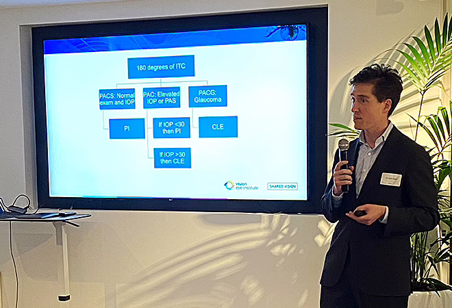 Dr Jack Kane speaking into a microphone while standing beside a screen bearing a PowerPoint slide with a clinical decision-making flowchart on it.