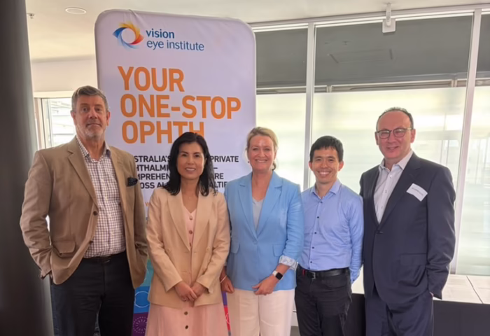 Left to right: A/Prof Tim Roberts, Dr Tess Huynh, VEI CEO Amanda Cranage, Dr Chris Go and Dr Lewis Levitz. They are standing shoulder-to-shoulder, and are positioned in front of a VEI sight that reads 'Your one-stop ophth.'
