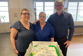 Three Windsor Gardens Day Surgery employees (including Director of Nursing Anne Sciacca and Manager of South Australian Operations, Gideon Sinclair). They are standing with their arms around each other, behind a Windsor Gardens Day Surgery birthday cake.