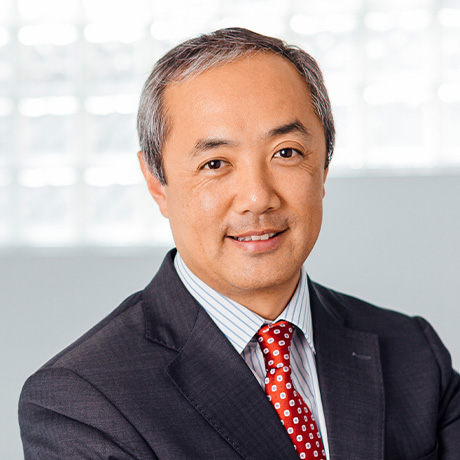 Headshot of Dr David Ng in a black suit and red tie in front of a white and grey textured wall in Chatswood Day Surgery