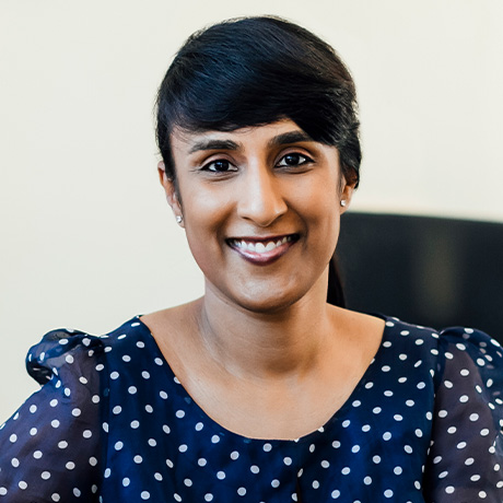 Headshot of Dr Rushmia Karim in a navy blue, polka dot dress in her consulting suite at Chatswood Day Surgery