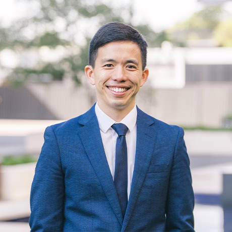 Outdoor portrait shot of Dr Christopher Go in a dark blue suit jacket over a pale blue, collared shirt and dark blue tie