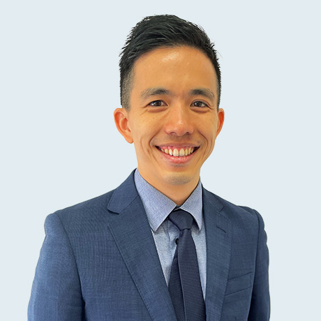 Headshot of Dr Christopher Go in a navy blue suit, light blue shirt and navy blue tie